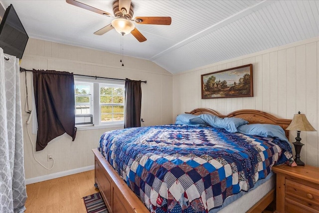 bedroom featuring ceiling fan, wooden walls, light wood-type flooring, and lofted ceiling