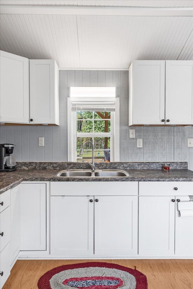 kitchen with white cabinets, light wood-type flooring, and sink