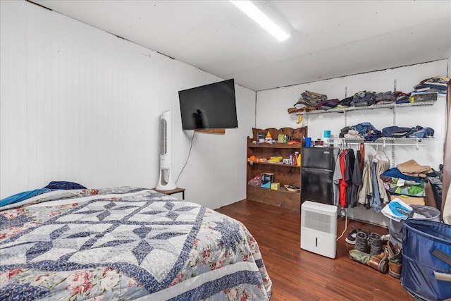 bedroom featuring wooden walls and dark hardwood / wood-style floors