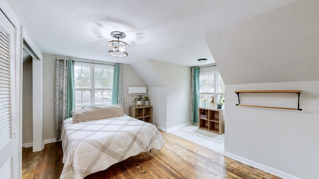 bedroom with multiple windows, lofted ceiling, and hardwood / wood-style flooring