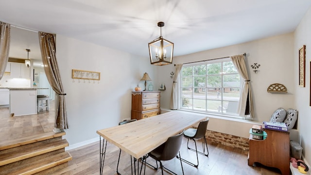 dining space with light hardwood / wood-style flooring and a notable chandelier