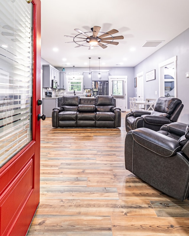 living room featuring light hardwood / wood-style flooring and ceiling fan