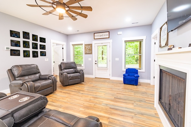 living room featuring light hardwood / wood-style floors, ceiling fan, and a healthy amount of sunlight