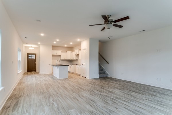 unfurnished living room featuring light hardwood / wood-style flooring, sink, and ceiling fan