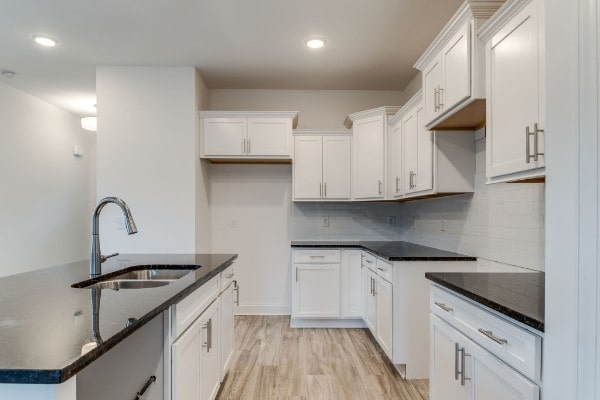 kitchen with light hardwood / wood-style floors, decorative backsplash, sink, and white cabinets