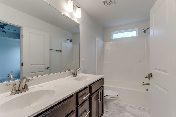 full bathroom featuring toilet, vanity, and bathing tub / shower combination