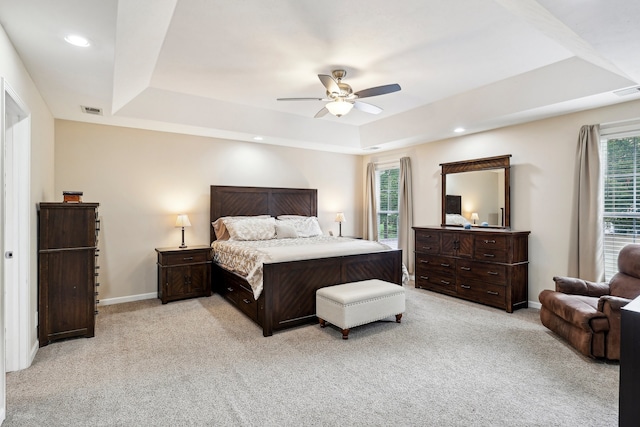 carpeted bedroom featuring ceiling fan and a tray ceiling