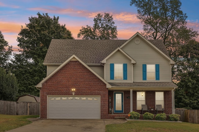 view of front of property featuring a yard, a garage, and covered porch