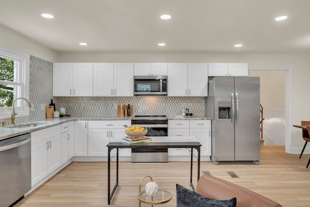 kitchen featuring white cabinets, stainless steel appliances, light wood-type flooring, and sink