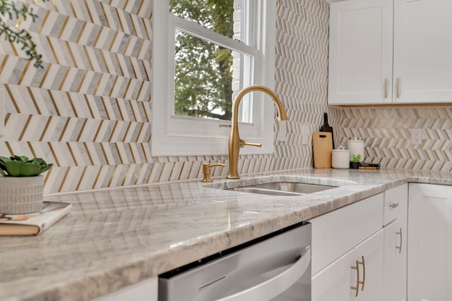 kitchen featuring sink, white cabinets, backsplash, light stone countertops, and stainless steel dishwasher