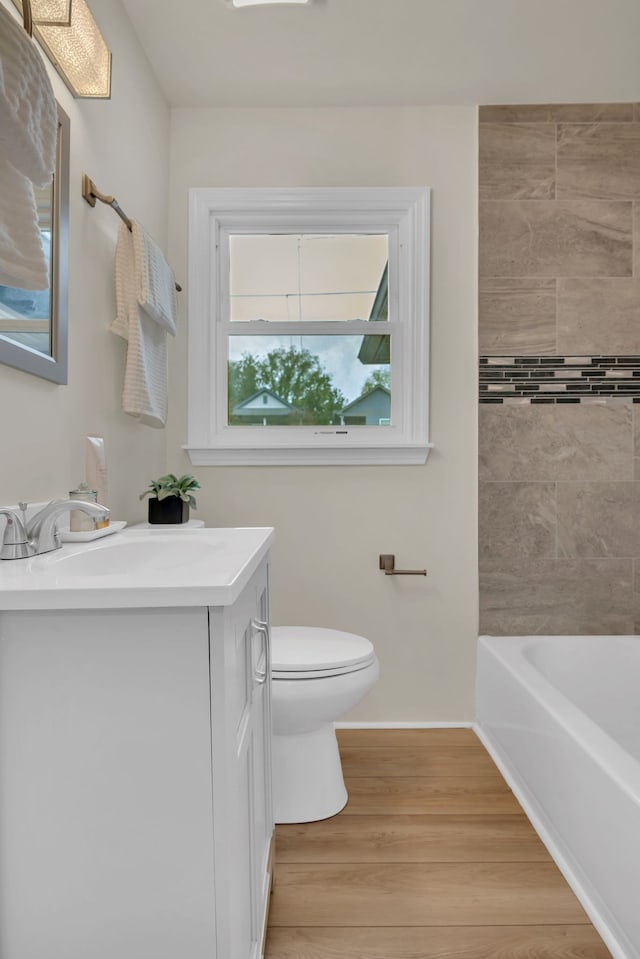 bathroom with a bathing tub, vanity, toilet, and hardwood / wood-style flooring