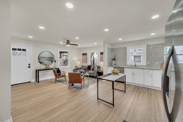 kitchen with ceiling fan, white cabinets, light hardwood / wood-style flooring, backsplash, and appliances with stainless steel finishes