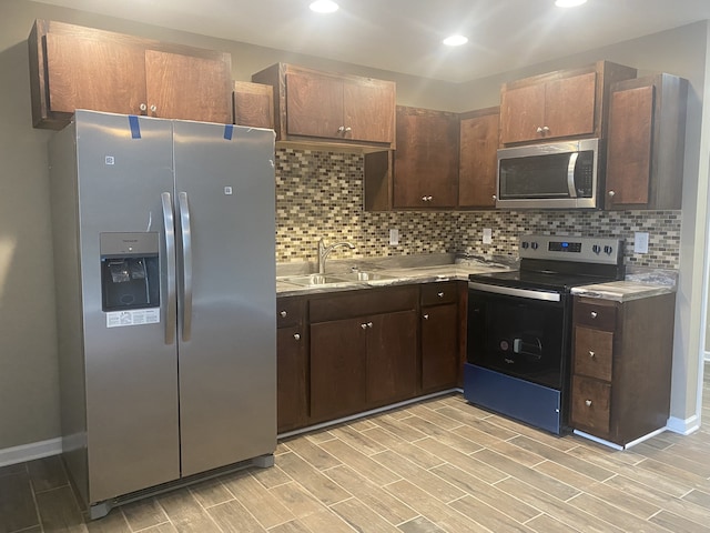 kitchen featuring light hardwood / wood-style floors, tasteful backsplash, sink, stainless steel appliances, and dark brown cabinetry