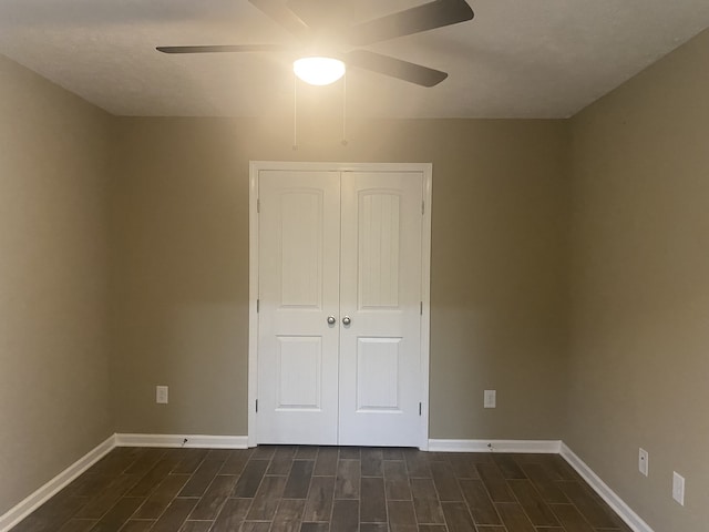 unfurnished bedroom featuring dark wood-type flooring, ceiling fan, and a closet