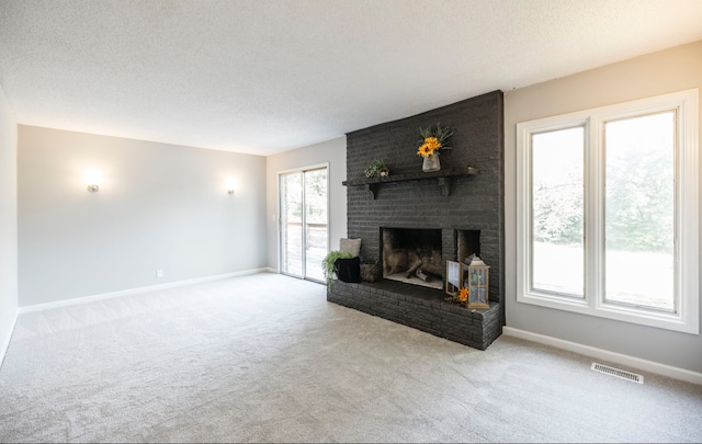 unfurnished living room featuring a textured ceiling, a fireplace, light colored carpet, and plenty of natural light