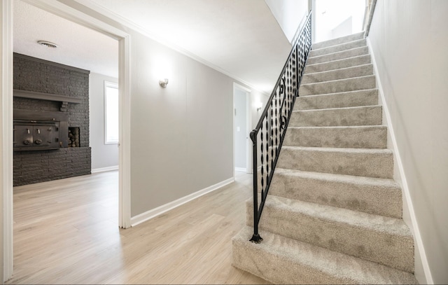 stairs featuring ornamental molding, hardwood / wood-style flooring, and a fireplace