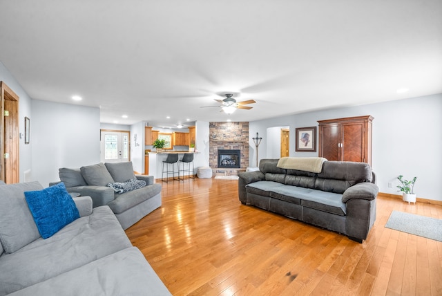 living room with a fireplace, ceiling fan, and light hardwood / wood-style flooring