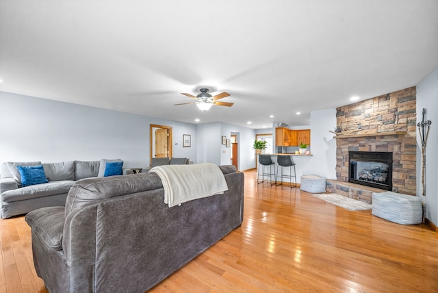 living room with light hardwood / wood-style floors, ceiling fan, and a fireplace