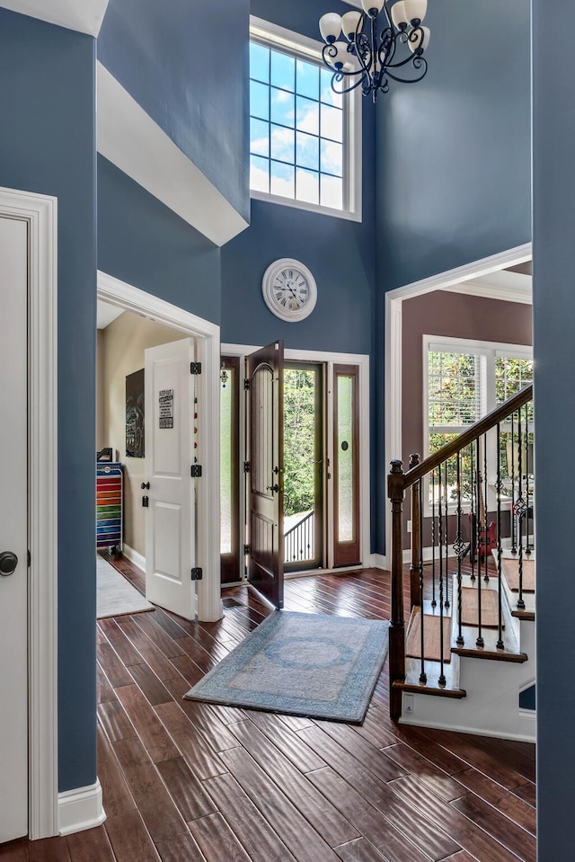 entrance foyer with a towering ceiling, an inviting chandelier, and dark wood-type flooring