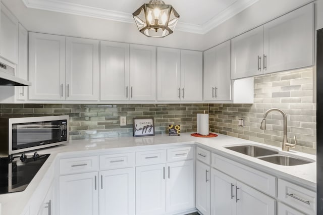 kitchen featuring black cooktop, decorative backsplash, white cabinetry, and sink