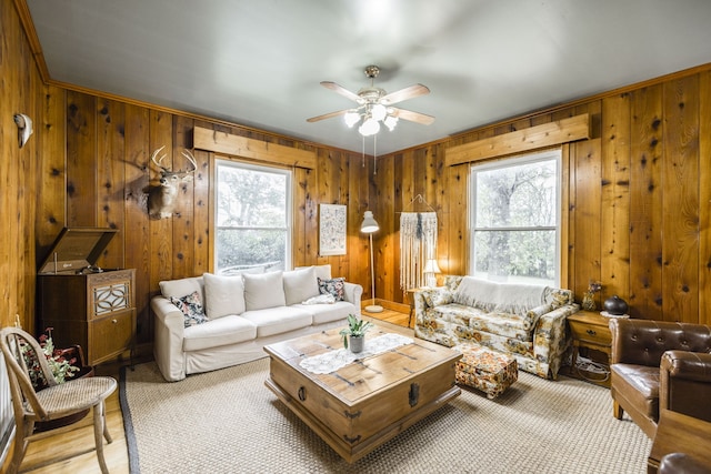 living room with wooden walls, light hardwood / wood-style floors, ceiling fan, and crown molding