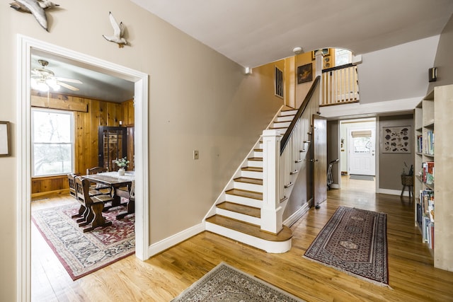 stairs with wood walls, hardwood / wood-style floors, and ceiling fan