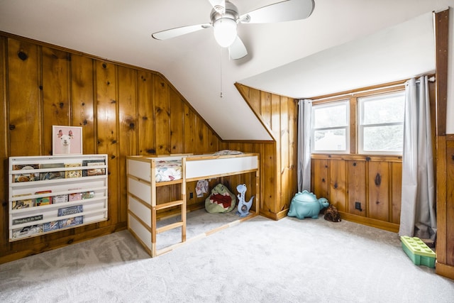 bedroom with lofted ceiling, wood walls, ceiling fan, and light carpet