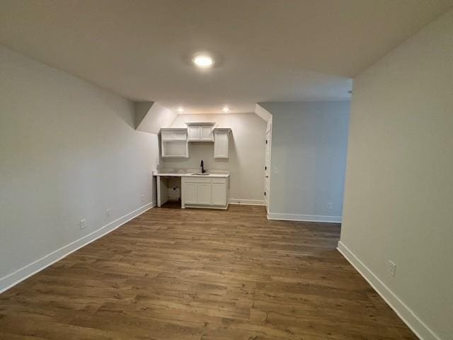 below grade area with recessed lighting, baseboards, a sink, and dark wood-style floors