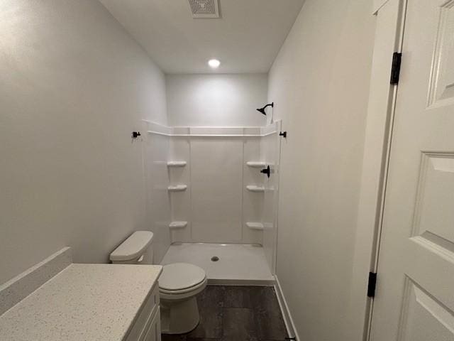 bathroom with visible vents, toilet, vanity, baseboards, and walk in shower