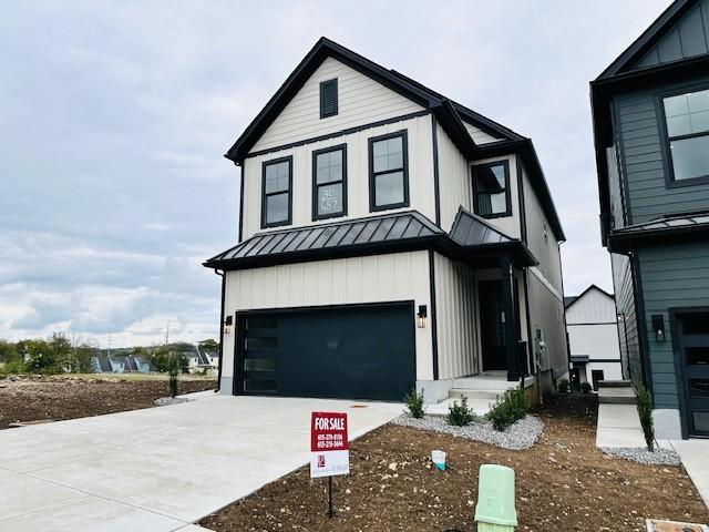 modern farmhouse featuring concrete driveway, board and batten siding, an attached garage, metal roof, and a standing seam roof