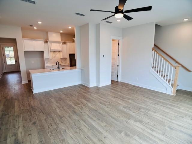 kitchen featuring white cabinets, light countertops, wood finished floors, visible vents, and a sink