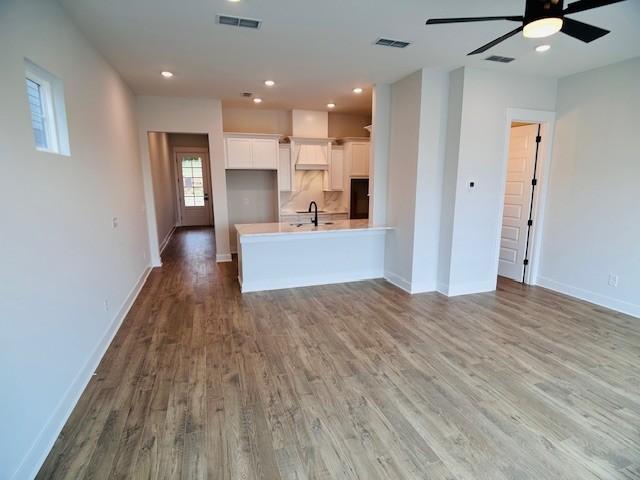 interior space featuring a peninsula, wood finished floors, visible vents, and light countertops