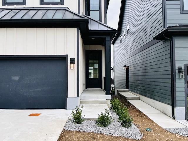 entrance to property featuring board and batten siding, an attached garage, and driveway