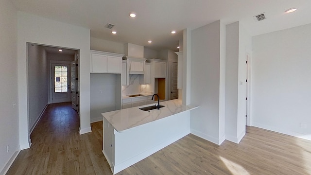 kitchen featuring white cabinetry, a sink, visible vents, and light wood-style flooring