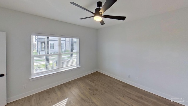 spare room featuring a wealth of natural light, wood finished floors, and baseboards