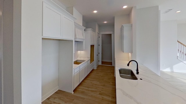 657 Gustaf Dr, Whites Creek, TN 37189 - kitchen featuring a sink, light stone counters, light wood finished floors, black electric stovetop, and white cabinetry