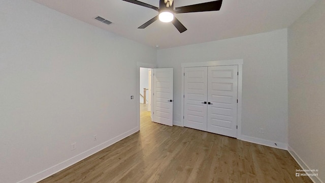 unfurnished bedroom featuring light wood finished floors, baseboards, visible vents, a closet, and ceiling fan