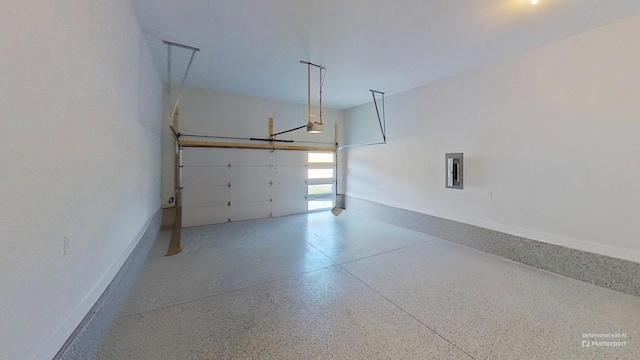 garage with a garage door opener, electric panel, and baseboards