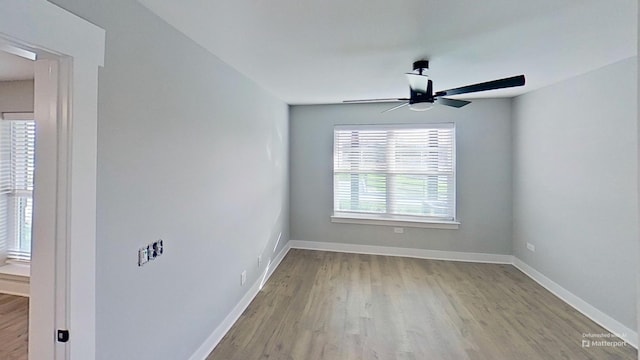 empty room with baseboards, wood finished floors, and a ceiling fan