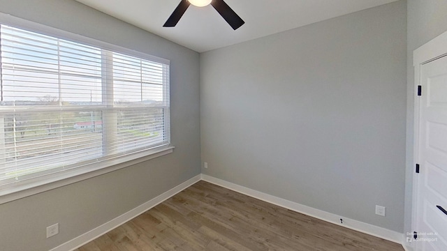 empty room with baseboards, wood finished floors, and ceiling fan