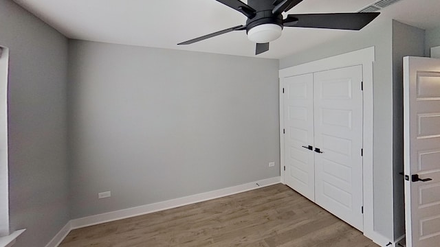 unfurnished bedroom featuring baseboards, a closet, wood finished floors, and a ceiling fan