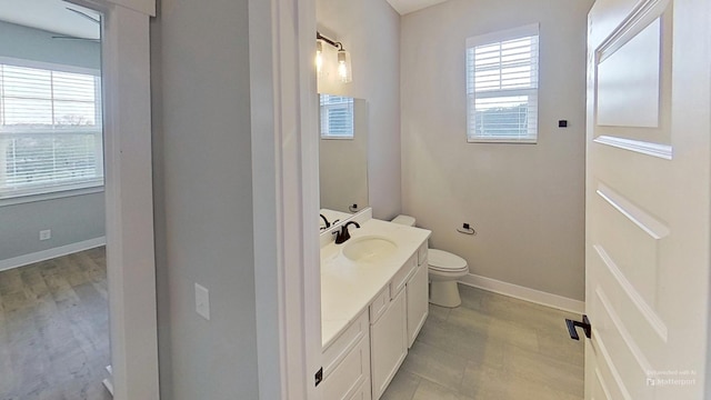 bathroom with baseboards, toilet, and vanity