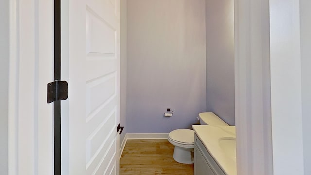 bathroom featuring toilet, wood finished floors, baseboards, and vanity