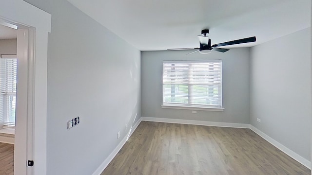 spare room with baseboards, wood finished floors, and a ceiling fan