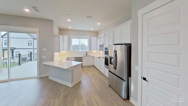661 Gustaf Dr, Whites Creek, TN 37189 - kitchen with appliances with stainless steel finishes, a sink, a peninsula, light wood finished floors, and white cabinetry
