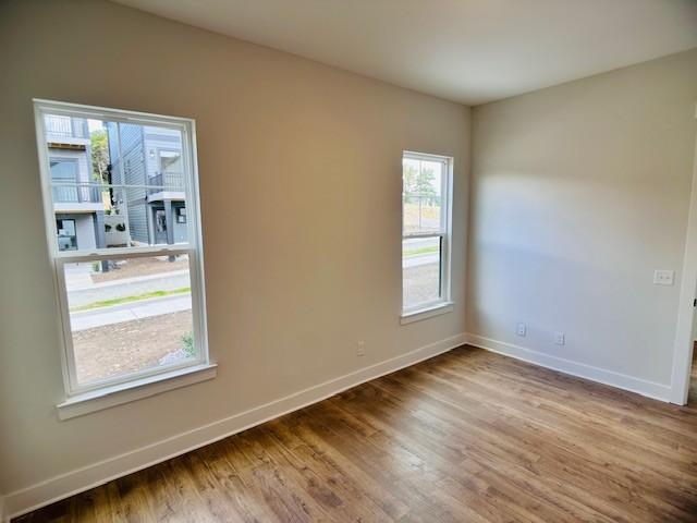 empty room featuring baseboards, plenty of natural light, and wood finished floors
