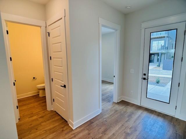 doorway with wood finished floors and baseboards