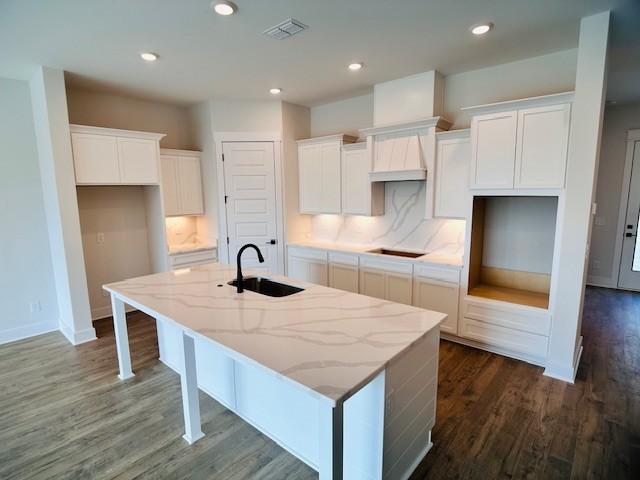 kitchen featuring a sink, a center island with sink, black electric stovetop, white cabinets, and dark wood-style floors