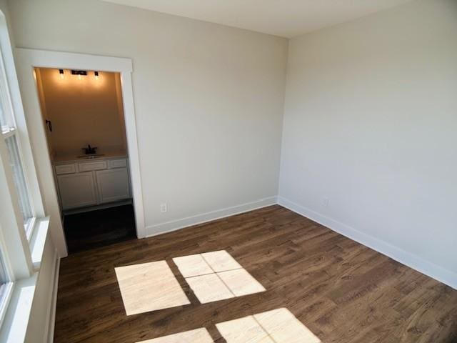 unfurnished bedroom featuring wood finished floors, baseboards, and a sink