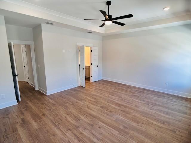 empty room with baseboards, wood finished floors, a raised ceiling, a ceiling fan, and recessed lighting